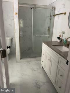 bathroom with vanity, toilet, and a shower with door