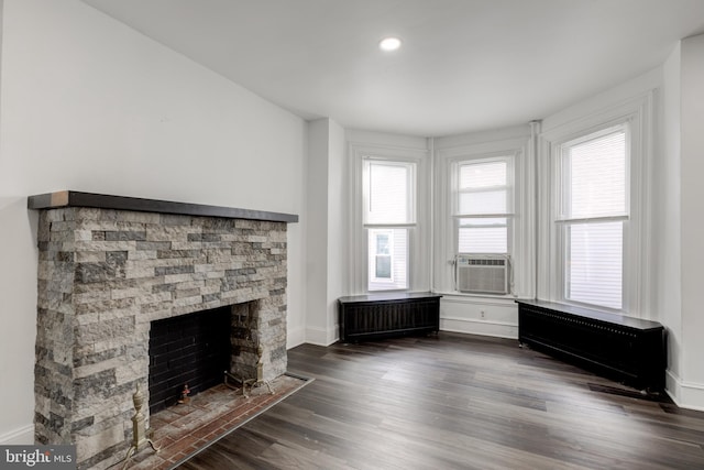 unfurnished living room featuring recessed lighting, radiator, dark wood-type flooring, a stone fireplace, and baseboards