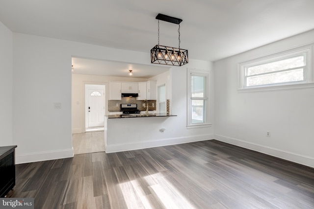 unfurnished living room with sink, dark wood-type flooring, and an inviting chandelier