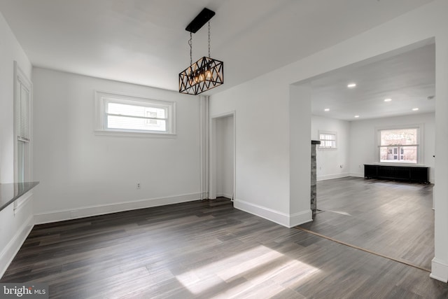 unfurnished dining area with dark wood-type flooring and a notable chandelier