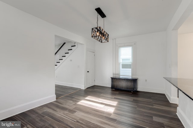 unfurnished dining area with dark wood-type flooring and a notable chandelier