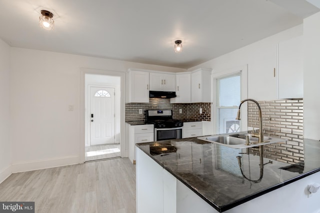 kitchen with stainless steel range with gas cooktop, sink, decorative backsplash, light hardwood / wood-style floors, and white cabinetry