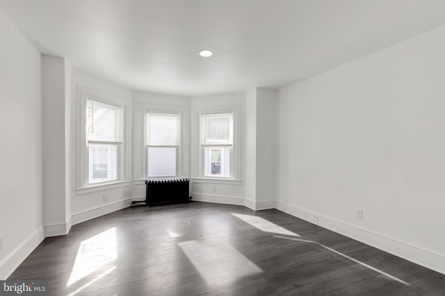 unfurnished living room with dark hardwood / wood-style floors and radiator heating unit