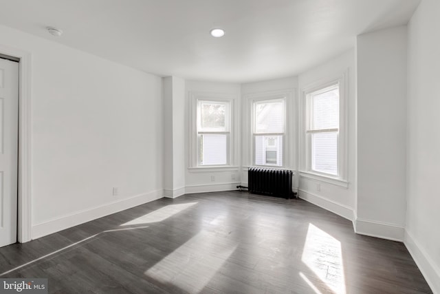 unfurnished room featuring dark hardwood / wood-style floors and radiator heating unit