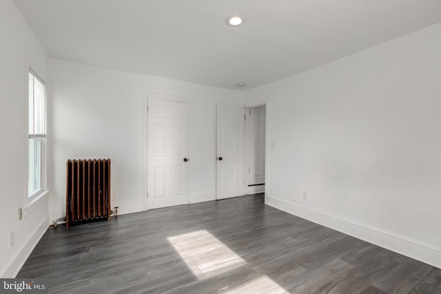 unfurnished room with radiator and dark hardwood / wood-style flooring