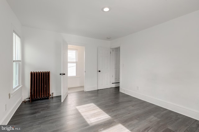 empty room with radiator and dark wood-type flooring