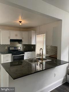 kitchen featuring white cabinets, stainless steel electric stove, sink, tasteful backsplash, and kitchen peninsula