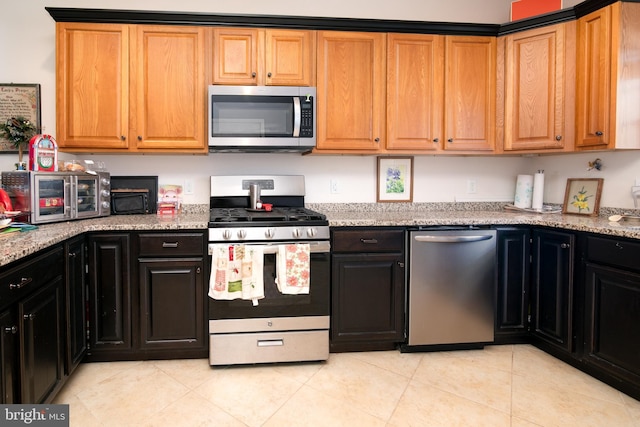 kitchen with light stone counters, stainless steel appliances, and light tile patterned floors