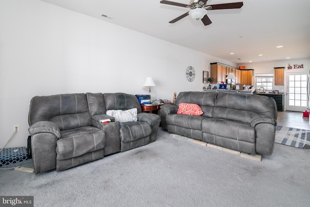 carpeted living room with ceiling fan