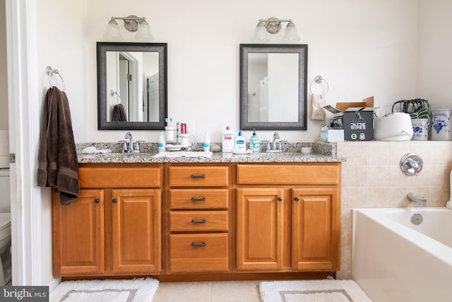 bathroom featuring double sink vanity, a tub to relax in, tile patterned floors, and toilet