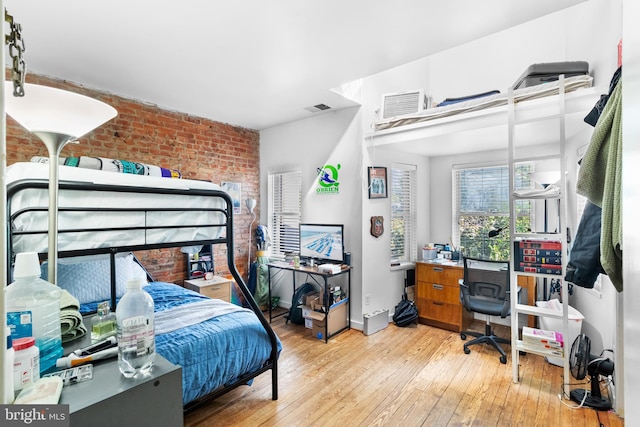 bedroom featuring hardwood / wood-style floors and brick wall