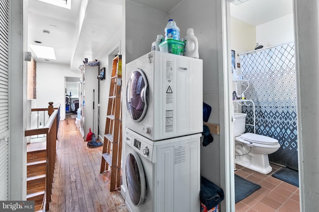 clothes washing area with stacked washer and clothes dryer and hardwood / wood-style flooring