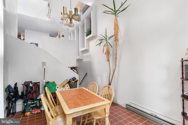 tiled dining room featuring a notable chandelier, baseboard heating, and track lighting