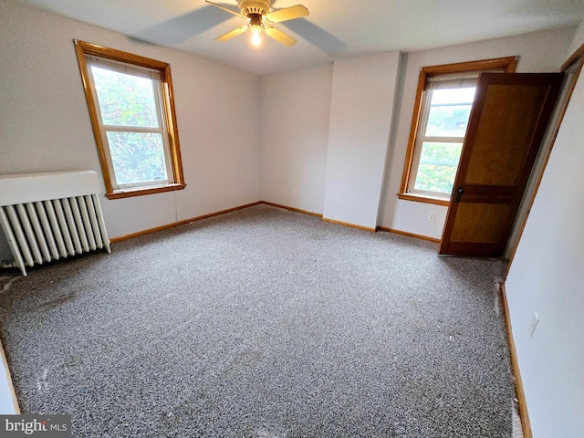 unfurnished room with radiator heating unit, ceiling fan, and carpet flooring