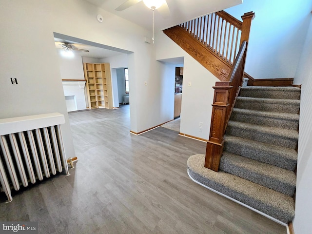 stairs with ceiling fan, hardwood / wood-style floors, and a high ceiling