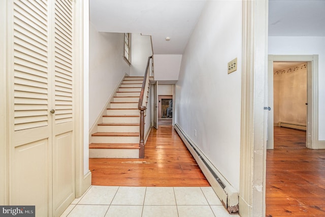 stairs featuring a baseboard heating unit and tile patterned floors