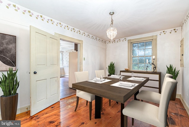 dining area with a notable chandelier, wood-type flooring, and baseboard heating