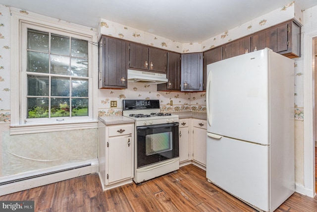 kitchen with under cabinet range hood, white appliances, light countertops, baseboard heating, and dark wood finished floors