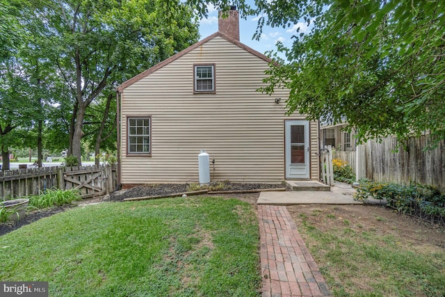 back of house with a yard, fence, and a chimney