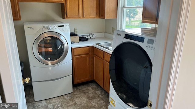 clothes washing area with washer and dryer and cabinets