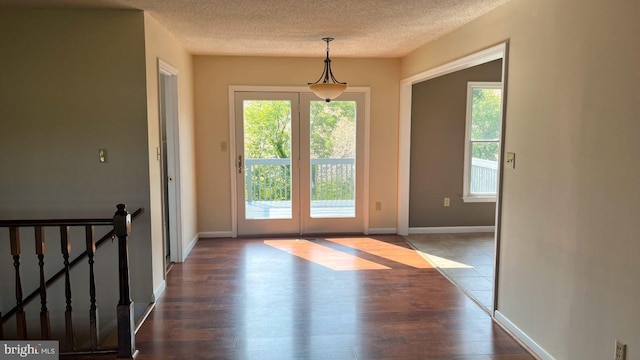 doorway to outside with french doors, dark hardwood / wood-style floors, and a textured ceiling