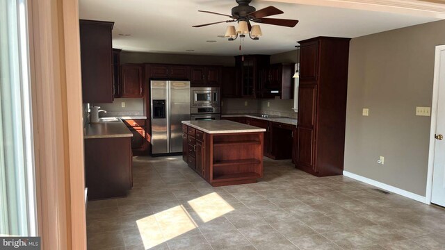 kitchen featuring a kitchen island, decorative light fixtures, sink, stainless steel appliances, and dark brown cabinets