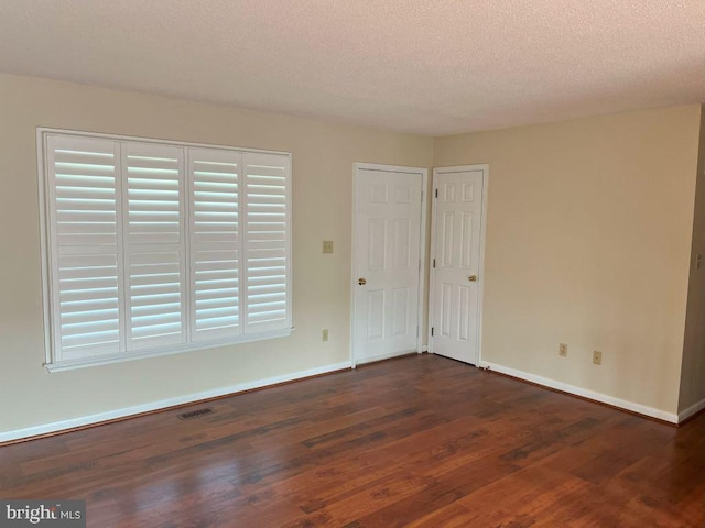 spare room featuring a textured ceiling and dark hardwood / wood-style floors