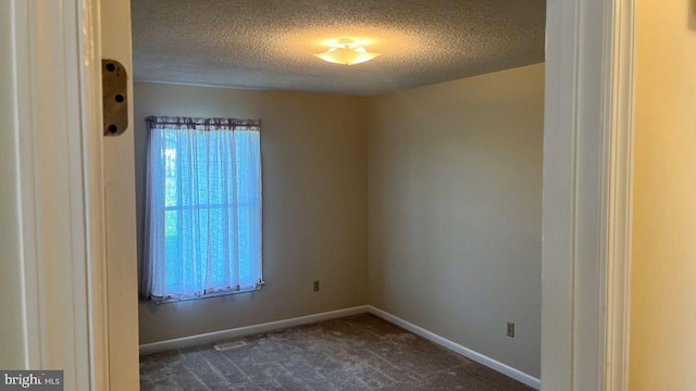 unfurnished room with dark colored carpet and a textured ceiling