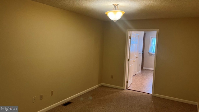 carpeted spare room featuring a textured ceiling