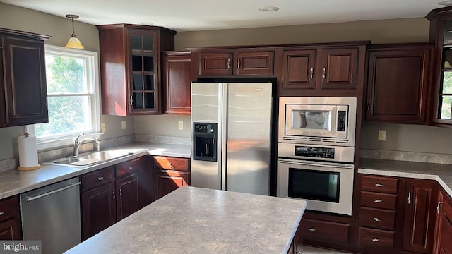 kitchen with appliances with stainless steel finishes, sink, and hanging light fixtures