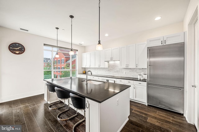 kitchen featuring white cabinetry, sink, dark hardwood / wood-style flooring, high end fridge, and a center island with sink