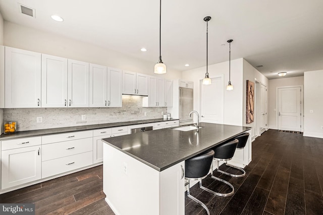 kitchen featuring pendant lighting, white cabinetry, sink, a kitchen breakfast bar, and a center island with sink