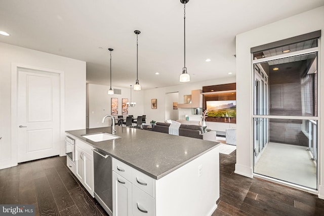 kitchen with white cabinetry, dishwasher, sink, hanging light fixtures, and a center island with sink