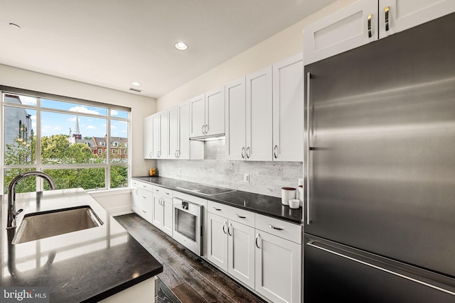 kitchen featuring white cabinetry, stainless steel built in fridge, sink, and oven