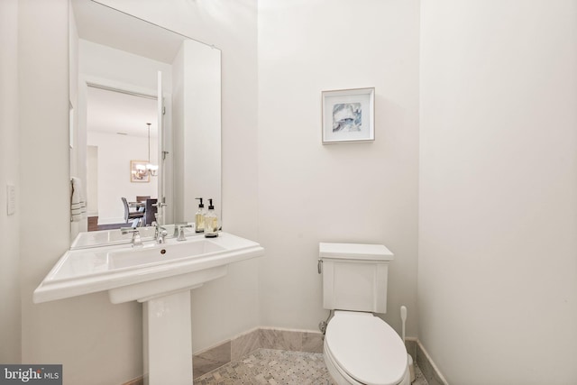 bathroom featuring sink, an inviting chandelier, and toilet