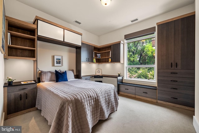 bedroom with built in desk and light carpet