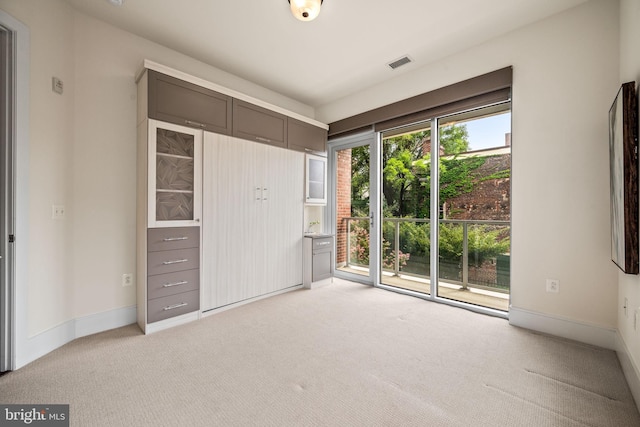 unfurnished bedroom featuring light carpet and access to outside