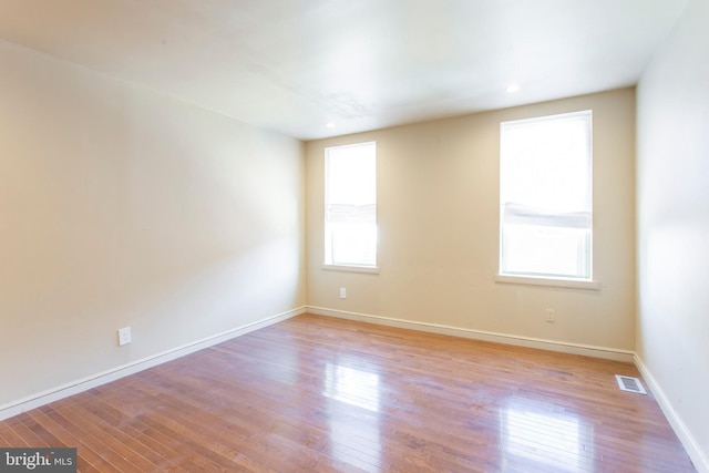 unfurnished room featuring light wood-type flooring, visible vents, and baseboards