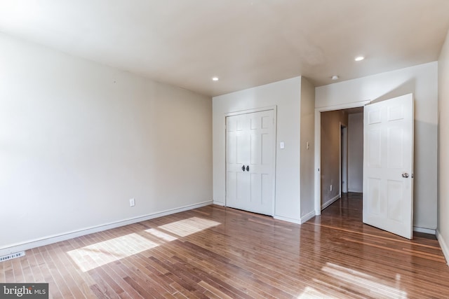 unfurnished bedroom with a closet, visible vents, baseboards, and wood finished floors