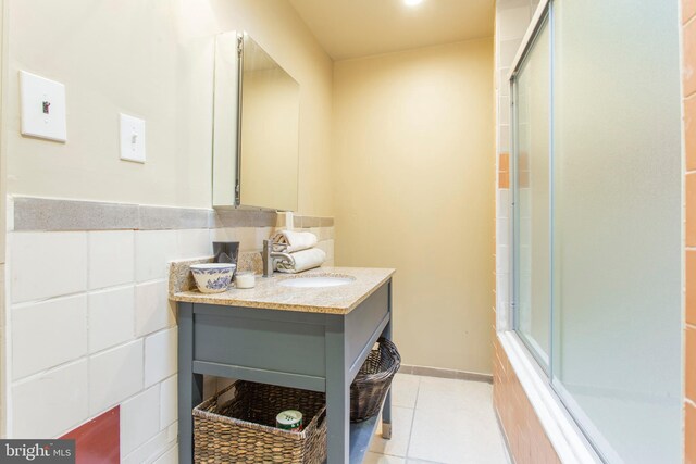 full bath featuring tile walls, a shower with door, vanity, and tile patterned floors