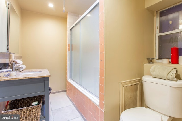 bathroom with bath / shower combo with glass door, baseboards, toilet, tile patterned flooring, and vanity