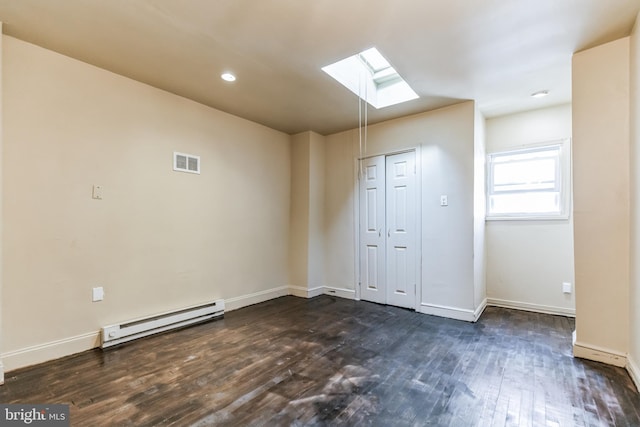 unfurnished room featuring a baseboard radiator, dark wood-style flooring, a skylight, visible vents, and baseboards