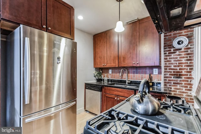 kitchen featuring dark countertops, a sink, hanging light fixtures, stainless steel appliances, and backsplash