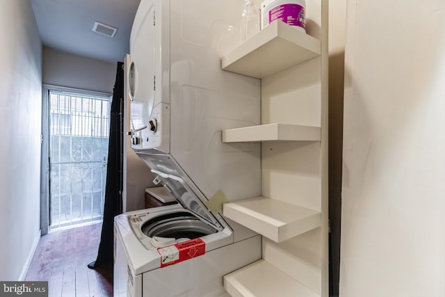 kitchen with baseboards, visible vents, stacked washer and clothes dryer, wood finished floors, and light countertops