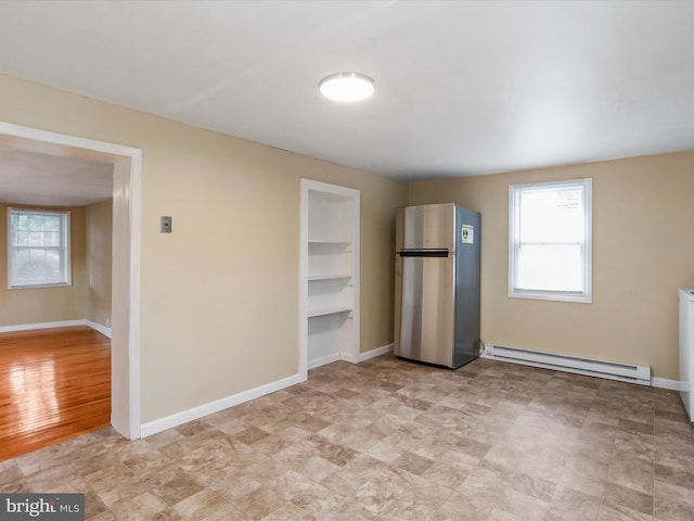 unfurnished bedroom with a baseboard radiator and stainless steel refrigerator