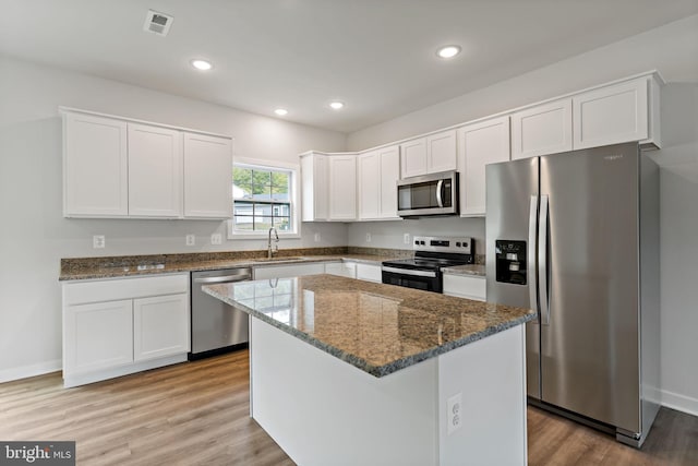 kitchen featuring sink, a center island, light hardwood / wood-style flooring, stainless steel appliances, and white cabinets