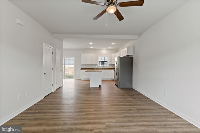 kitchen featuring a kitchen island, stainless steel refrigerator, white cabinetry, ceiling fan, and light wood-type flooring