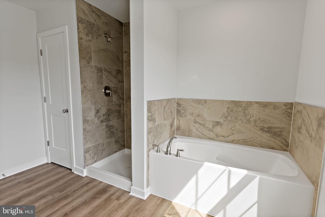 bathroom featuring hardwood / wood-style flooring and plus walk in shower