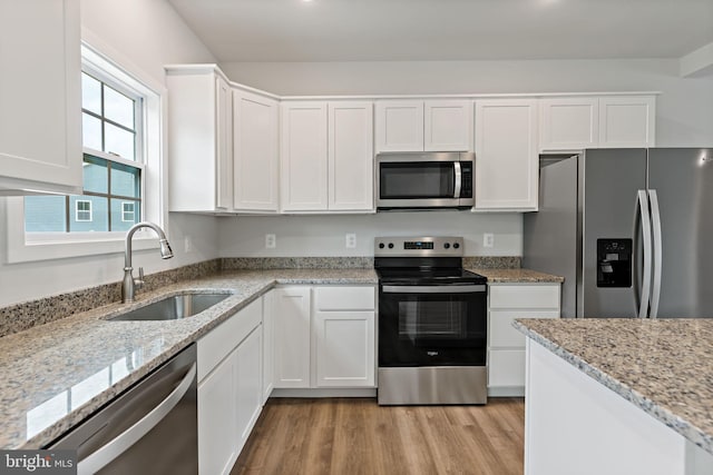 kitchen with sink, light hardwood / wood-style flooring, stainless steel appliances, light stone counters, and white cabinets