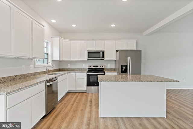 kitchen with sink, white cabinetry, light stone counters, a center island, and appliances with stainless steel finishes